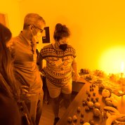 Photo with orange cast shows Lafer-Sousa chatting with 2 other people.