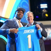 Johnson and NFL commissioner hold up jersey with name on it.