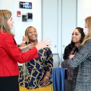 Four women talk informally before start of event.