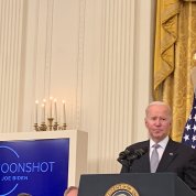 President Joe Biden at a White House East Room podium.