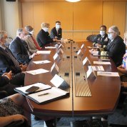 Masked people sit around a conference table