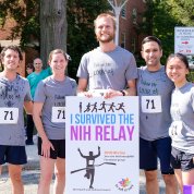Five runners smile holding a sign that says "I survived the NIH Relay."