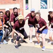 Team runners and supporters strike a running posture in front of Bldg. 2.