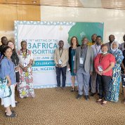 A group of researchers gather on either side of green and white H3Africa Consortium backdrop.