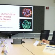 Kaplan stands in conference room, with slide projected beside her.