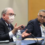Seated at a conference table, Tabak (l) gestures toward Jha (r).