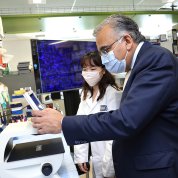 Jha leads over equipment as Woo in labcoat looks on.