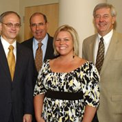 Three men and a woman smile into camera