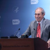 Gallin at podium with NIH logo backdrop behind him