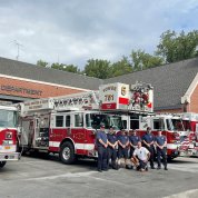 Fire fighters stand in front of fire truck outside the NIHFD apparatus bay.