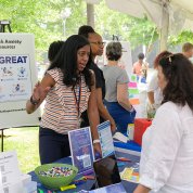 Staff stand near "Be Great" poster, discussing mental health resources.