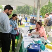 Staff stop at an information table under a tent at the fair.