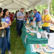Smiling staff talk with volunteers, including Jeffrey Potts in yellow mental health awareness shirt, at a biosafety booth.