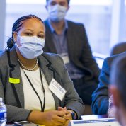 Aklin, seated and masked, addresses the minister.