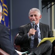 Fauci seated, holds mic