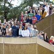 Large group of fellows stand together outside, winding around a staircase