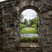 A stone wall and alcove, looking through to a garden and stone building beyond