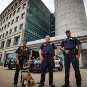 Three uniformed officers stand with a K9 dog in front of the Gateway Visitor Center