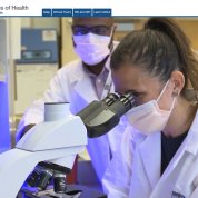 Screenshot of homepage shows a female scientist looking into a microscope with a colleague looking on, with Campus Map, Virtual Tour and Tour at a Glance buttons and several top navigation tabs as well