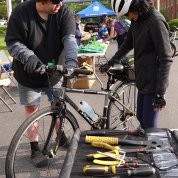 A mechanic looking at bicycle with rider nearby, a table of bike tools next to them