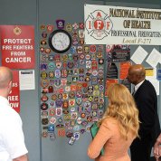 Firemen show Schwetz and Johnson a wall covered in firefighter badges.