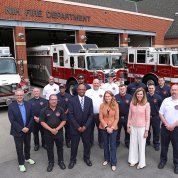 NIH leaders pose with NIH firefighters in front of apparatus bay outside NIH fire station.