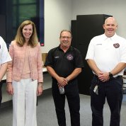 NIH leaders and firehouse leaders stand posing together in the station's classroom.