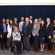 The group of fellows pose with Tabak, Schwetz next to U.S. and HHS flags.