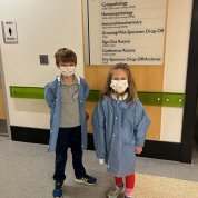 Two masked children in lab coats pose in the CC.