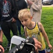 Boy in yellow shirt looks at black and white snake.