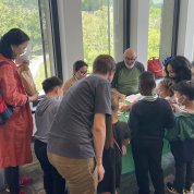 Parents and kids crowd around green table.