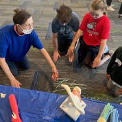 Kids and an adult volunteer look at a model of a joint.