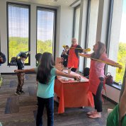 Kids and NIAMS volunteers stretch around a red table.