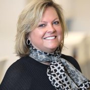 A headshot of Sofranko, a blond woman wearing a black sweater and black-and-white patterned scarf.