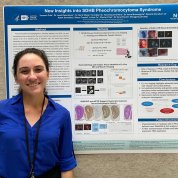 Woman in blue shirt poses in front of her research poster