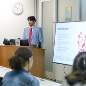 Man at lectern with students at desks in foreground
