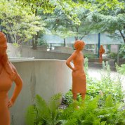 Life-sized orange statues of women grace the CC courtyard, with foliage all around.