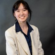 Tran in an off-white blazer against a gray background. 