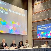 Several people seated at a long table with the title slide projected behind them