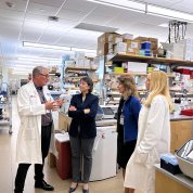 A group stands together talking, in a lab.