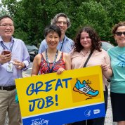 A group stands together holding yellow sign reading "great job" with a sneaker on the front