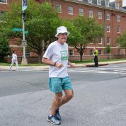 Man in shorts, t-shirt, hat jogs