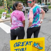 Two smiling women from behind, heads turned forward, with Great Job sign in front