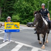 An officer on horseback next to woman holding Great Job sign