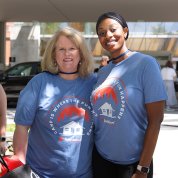 Two smiling women wearing blue camp t-shirts.
