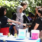 Volunteers standing in front of a table accept donations from supporters.