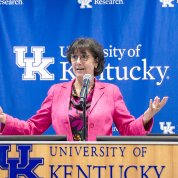 Woman speaking at podium with UK logo and backdrop