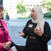 Two women chat. One wears a traditional head covering.