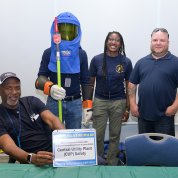 A group from the utility plant pose by table with one wearing face shield.