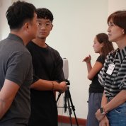 A woman and two men converse.